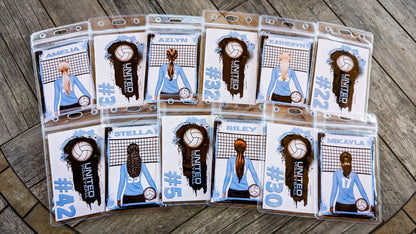 Examples of personalized volleyball bag tags in clear holders, showing player names, blue uniforms and jersey numbers on front and back designs.